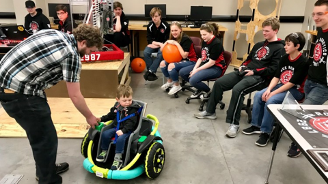 Tyler Jackson assists his son Cillian as Farmington High School Robotics Team members look on. Photo: Boyd Huppert, KARE